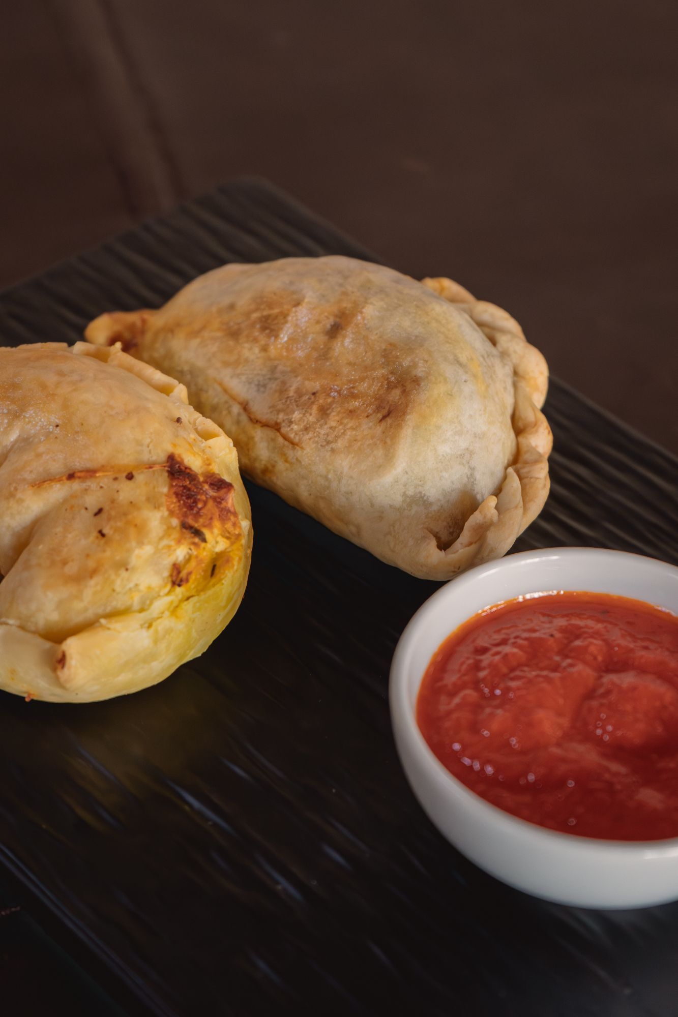 Duo de empanadas de carne cortada a cuchillo y de quesos, acompañadas con yasjua de morrones asados