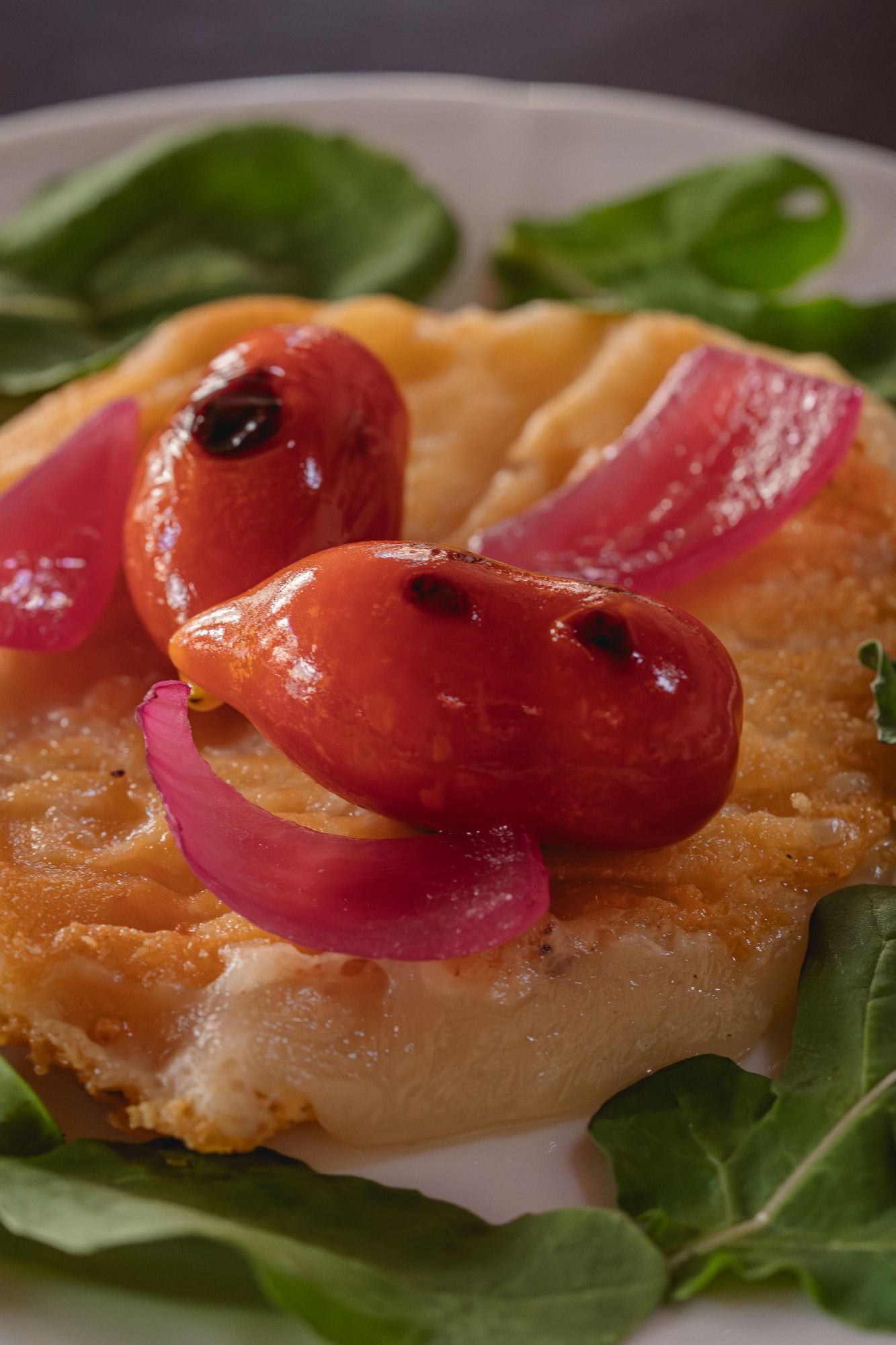 Provoleta de queso de cabra con tomates asados, pickles y rúcula